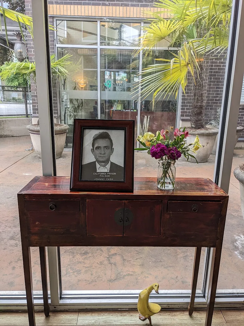 An antique red console table with fresh flowers and a framed Johnny Cash portrait.