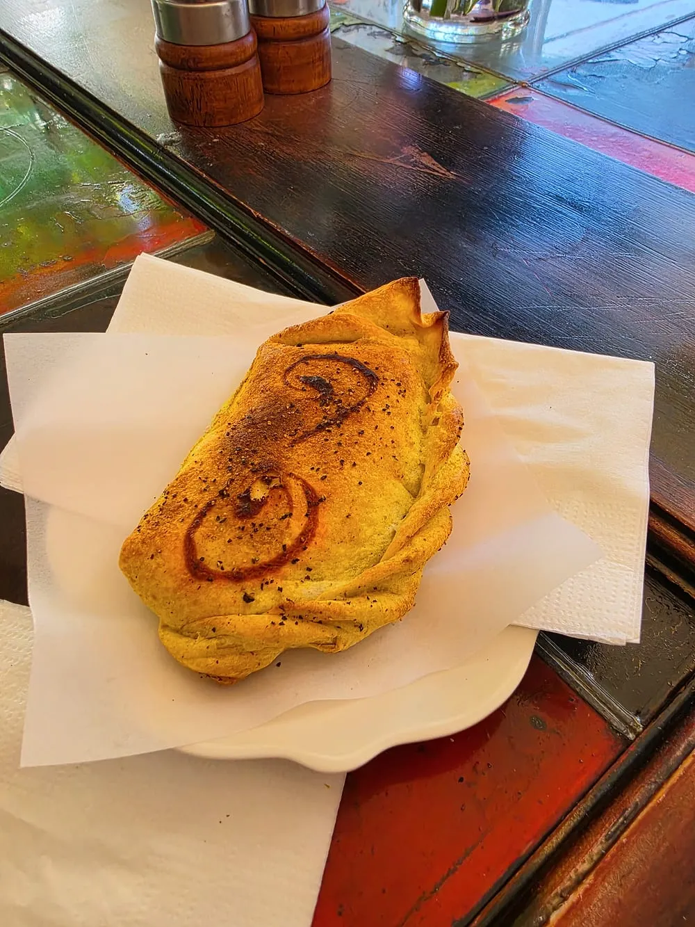 A café-made samosa, golden and scored, on a scalloped white plate at Cafe Argento.